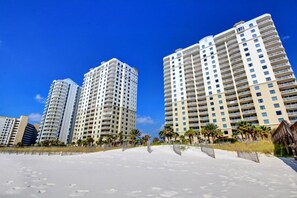Ein Strandhotel mit mehreren Hochhäusern, einem Sandstrand und Palmen.