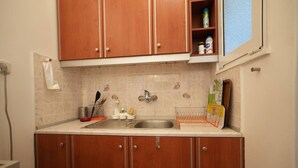 A small kitchen with wooden cabinets, a sink, and a window above the countertop. - Heart of Athens 1 Bedroom (Athens)
