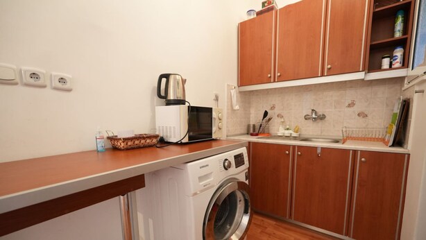 A compact kitchen with a washing machine, microwave, and wooden cabinets. - Heart of Athens 1 Bedroom (Athens)