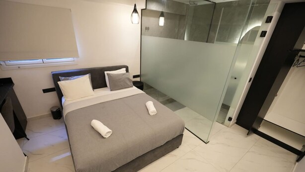 Una camera da letto moderna con un letto, un comodino e un divisorio in vetro.