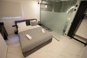 A modern bedroom with a bed, bedside table, and a glass partition. - Signature Suites - Stadiou (Athens)