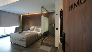 Un dormitorio moderno con una cama grande, un box de ducha de vidrio y una puerta de madera con el nombre 