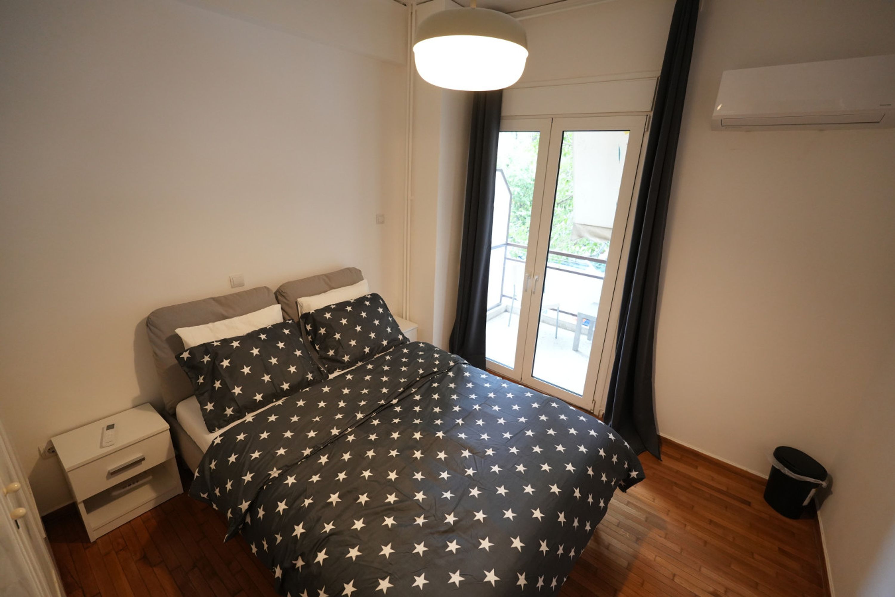 A bedroom with a bed, a nightstand, a window, and a door.