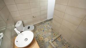 Ein Badezimmer mit einem weißen Waschbecken, einer Toilette mit gemustertem Sitz und einer Duschkabine.