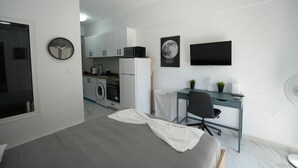Un dormitorio moderno con cama, escritorio y kitchenette.