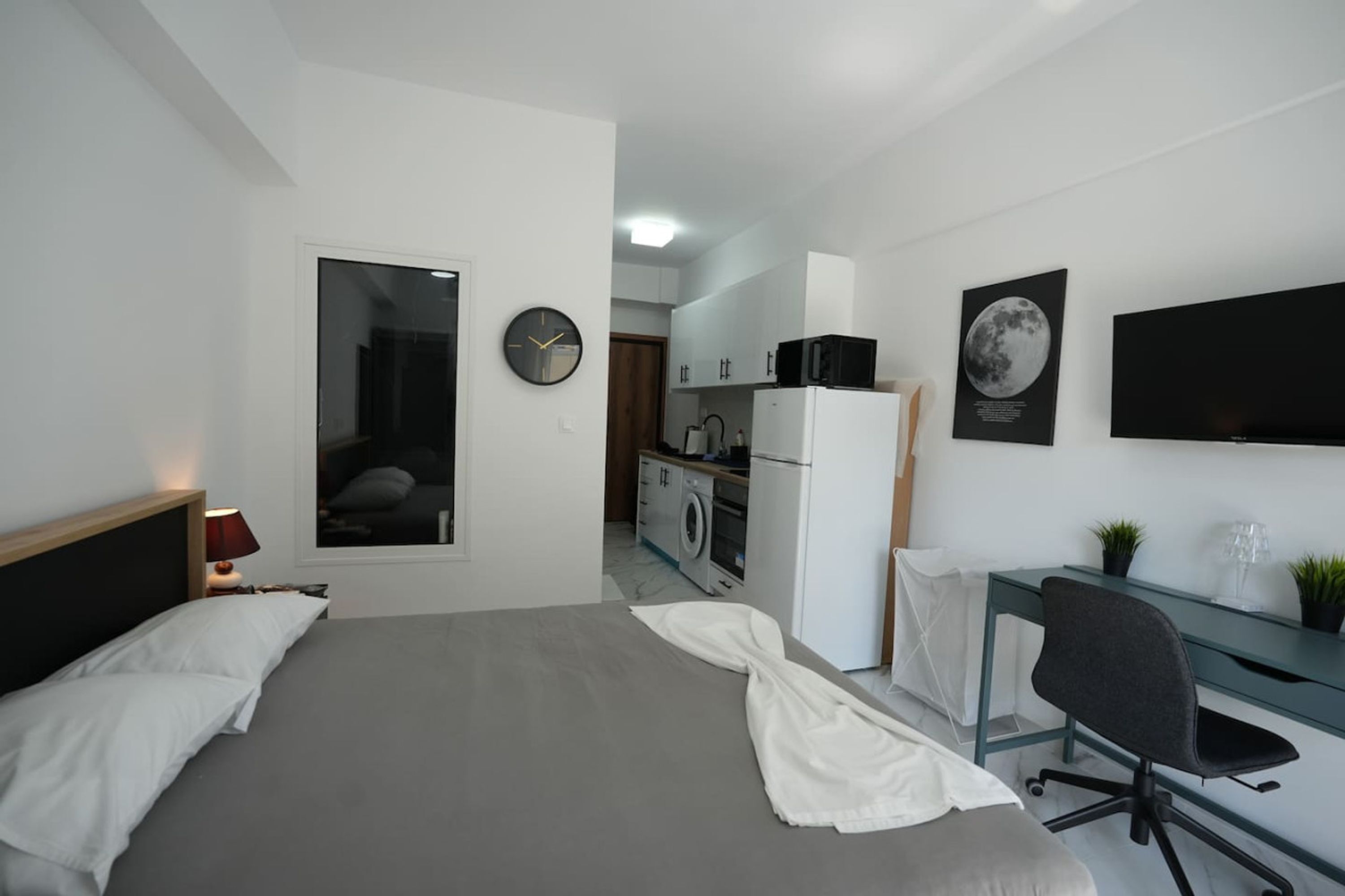 Una habitación de hotel moderna con cama, escritorio, silla y kitchenette.