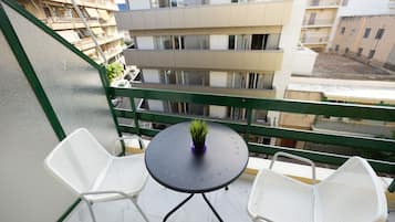 Ein Balkon mit zwei weißen Stühlen und einem Tisch mit einem Blumentopf.