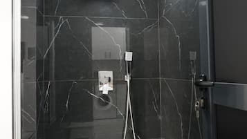 Ein modernes Badezimmer mit Duschkabine aus Glas, Marmorwänden und Fliesenboden.