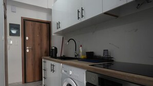 Cocina compacta equipada con lavadora, horno y encimera de madera.