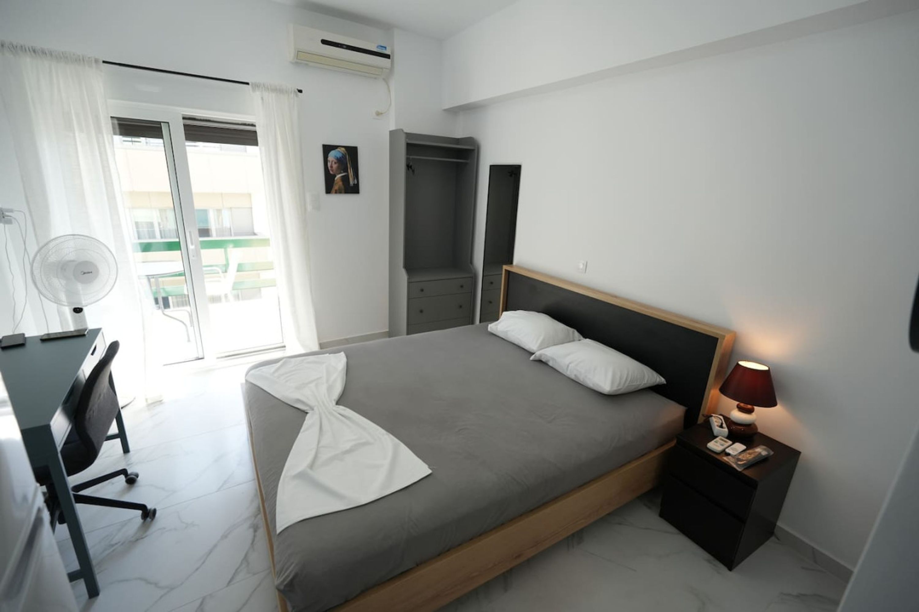 Un dormitorio moderno con cama, mesita de noche y escritorio con silla.
