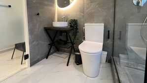 A modern bathroom with a white sink, a toilet, and a shower area. - Signature Suites - Athinas (Athens)