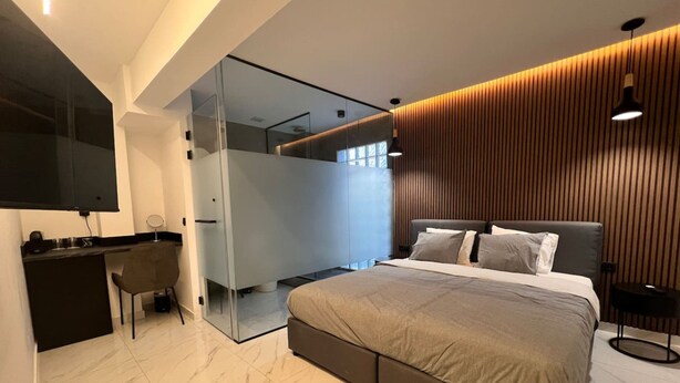 A modern bedroom with a bed, desk, and a large mirror. - Signature Suites - Athinas (Athens)