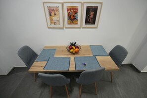 A conference table with four chairs, a fruit bowl, and three framed posters on the wall. - Loutraki Seaview Firstline (Loutraki-Agioi Theodoroi)