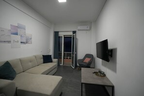 A modern living room with a sofa, a small table, and a TV mounted on the wall. - Loutraki Seaview Firstline (Loutraki-Agioi Theodoroi)