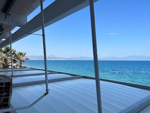 A view from a covered outdoor area with a metal roof, overlooking a body of water and distant mountains. - Loutraki Seaview Firstline (Loutraki-Agioi Theodoroi)