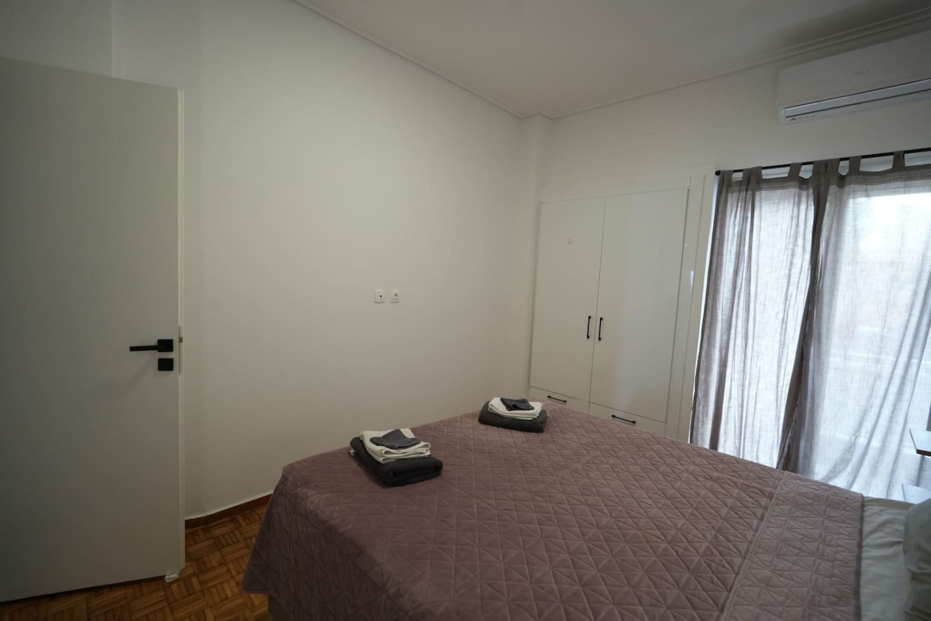 A room with a bed, a wardrobe, and a door.