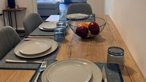 A dining area with a wooden table set for four, including plates, cutlery, and a fruit bowl. - Loutraki Seaview Firstline (Loutraki-Agioi Theodoroi)