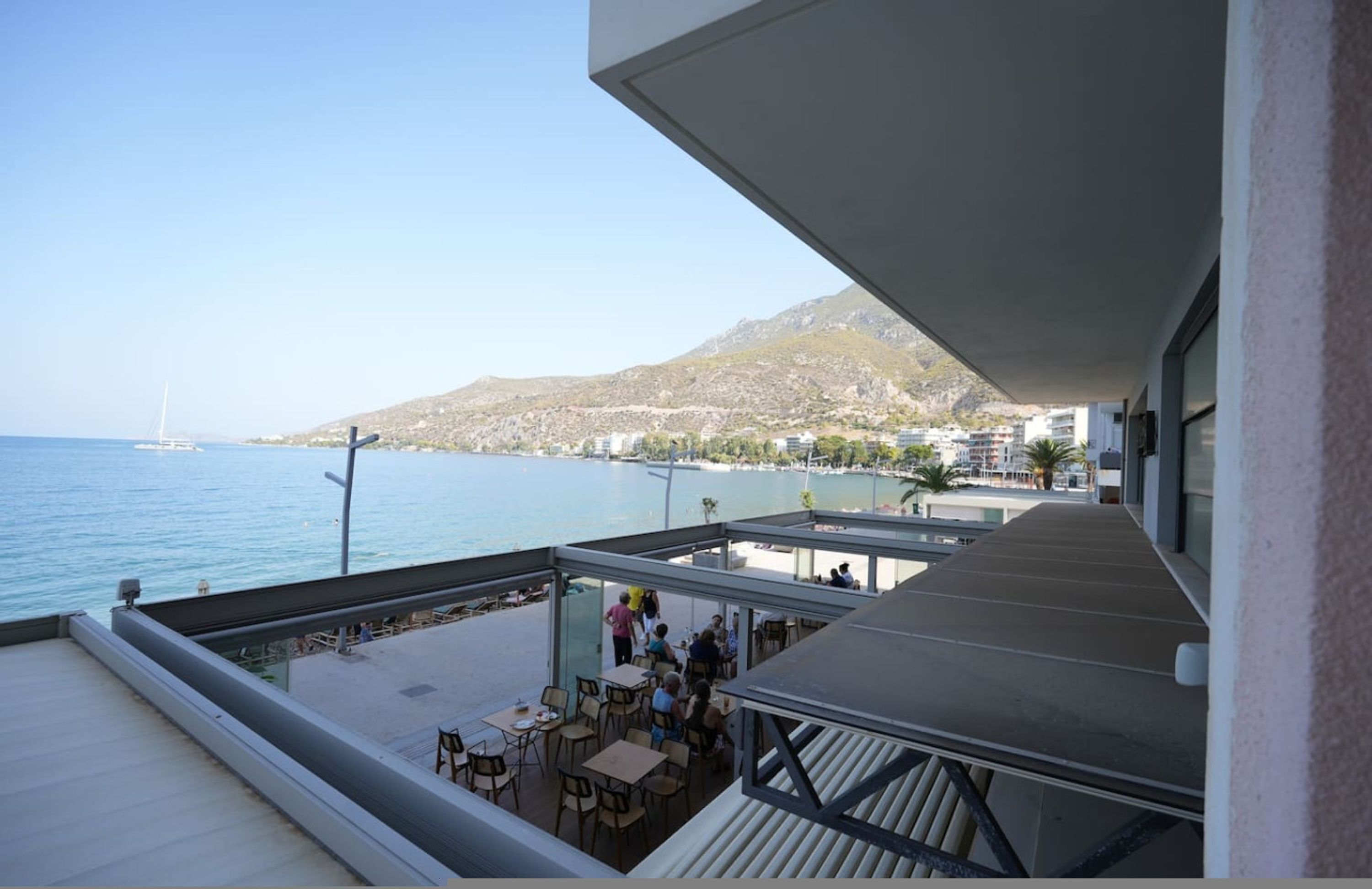 A balcony with outdoor seating overlooking a beach and the sea.