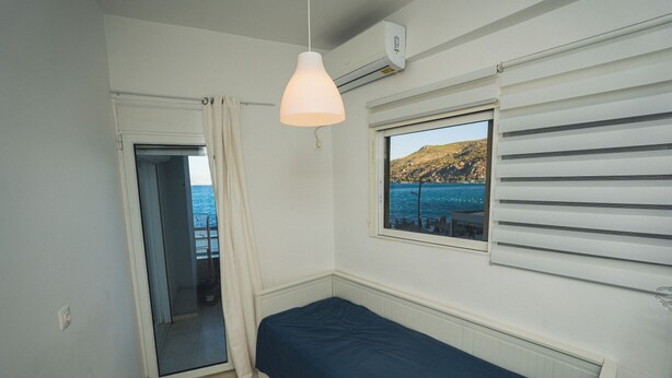 A small, single-bed room with a view of the sea through a window. - Best View Loutraki 2 Bedroom (Loutraki-Agioi Theodoroi)