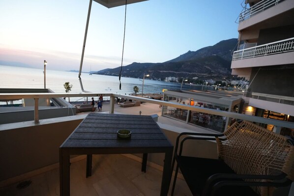 A balcony with a table and chairs overlooking a body of water and a mountainous landscape. - Best View Loutraki 2 Bedroom (Loutraki-Agioi Theodoroi)