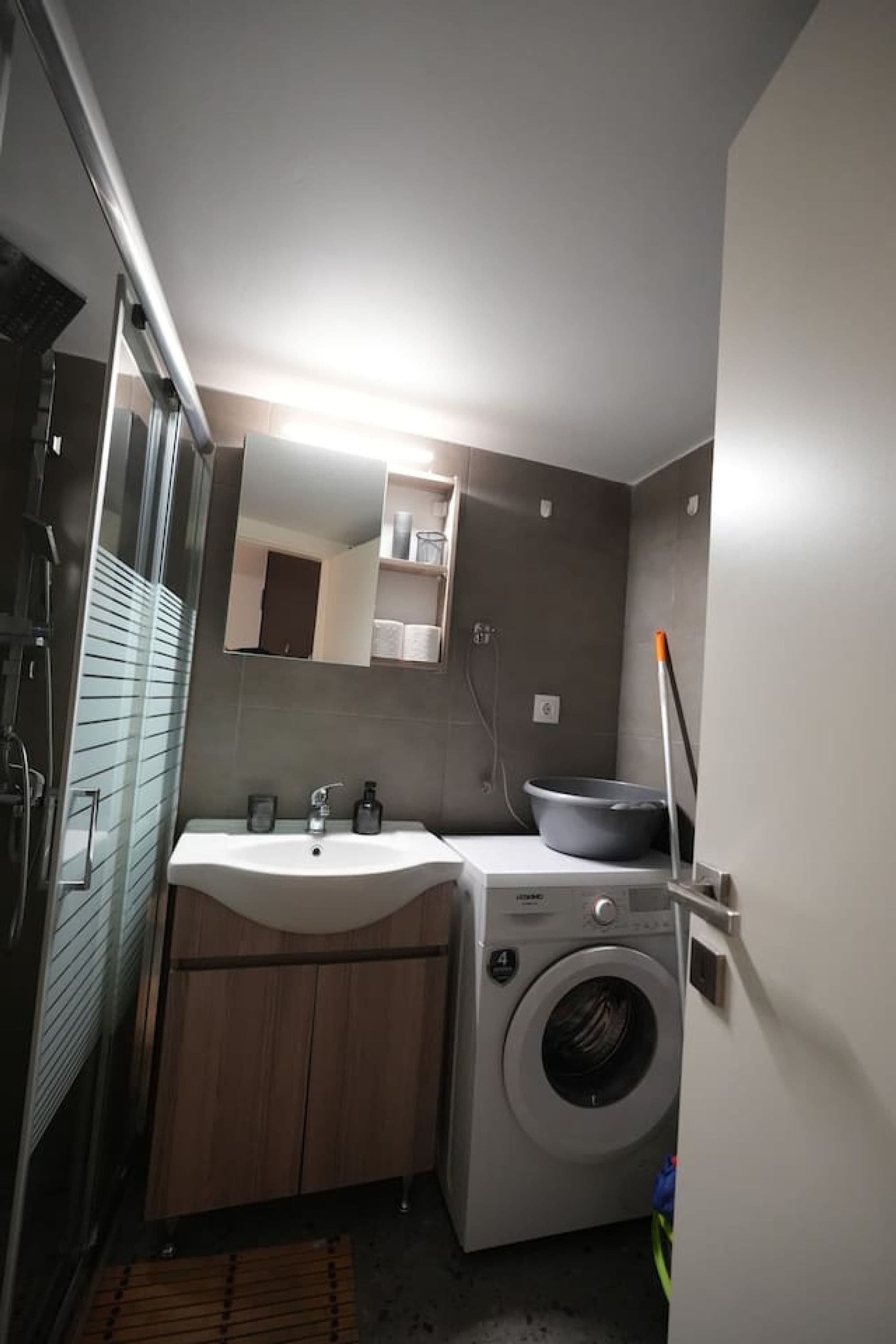 A compact bathroom with a sink, mirror, and washing machine.