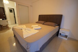A neatly made bed with a brown headboard, a small bedside table, and a white nightstand. - Beachfront Escape Seaview (Loutraki-Agioi Theodoroi)