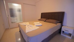 A neatly made bed with a headboard, a bedside table, and a sliding glass door. - Beachfront Escape Seaview (Loutraki-Agioi Theodoroi)