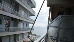 Un balcón con vista al mar, una silla metálica y una barandilla.