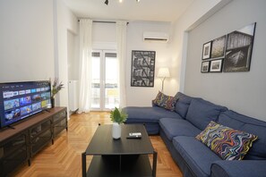 A living room with a TV, sofa, coffee table, and artwork on the wall. - Ilysia s Retreat Cozy 1 Bdrm Apartment (Athens)