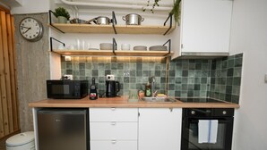A compact kitchen with white cabinets, a wooden countertop, a microwave, a coffee maker, a sink, and a dishwasher. - The Extravagant Studio in Pagkrati Near Stadium (Athens)