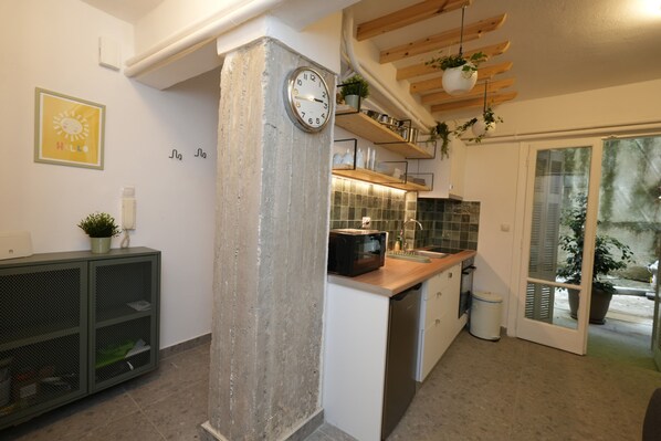 Une cuisine moderne dotée d’un four à micro-ondes encastré, d’étagères en bois et d’une horloge murale.