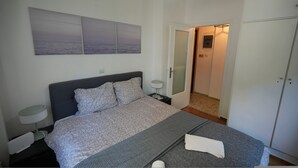 Ein Schlafzimmer mit einem Bett, Nachttischen, einer Lampe und einer Tür zu einem Badezimmer.