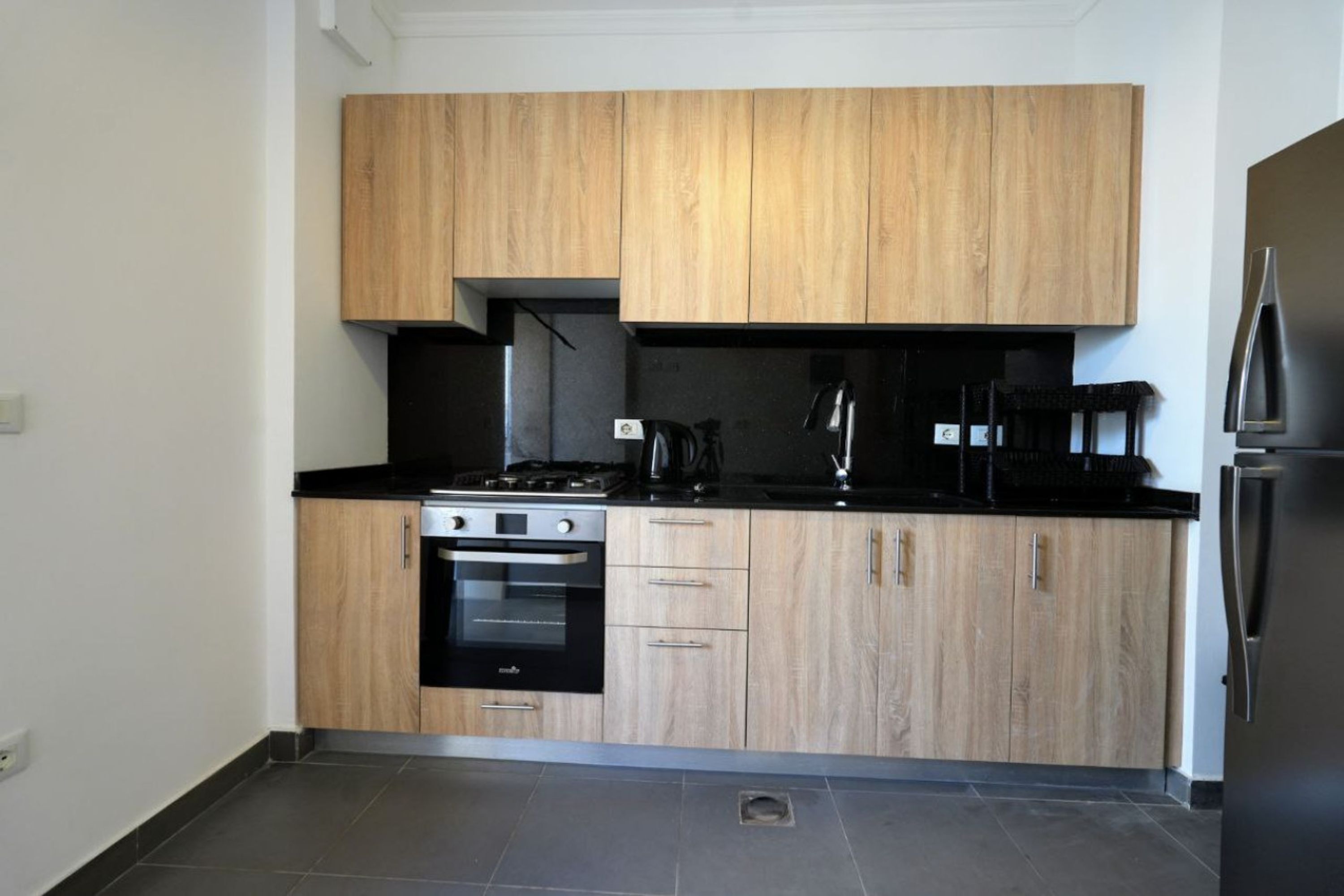 Une cuisine moderne avec des meubles en bois, une cuisinière, un four et un réfrigérateur.