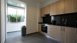 A modern kitchen with wooden cabinets, a black countertop, and a window with a view of greenery. - The Purple Apartment Badaro 3 Bdrm 24 7 Electric (Beirut)