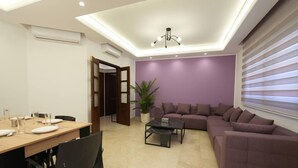 A modern living room with a dining area, featuring a sofa set, a coffee table, and a dining table with chairs. - The Purple Apartment Badaro 3 Bdrm 24 7 Electric (Beirut)