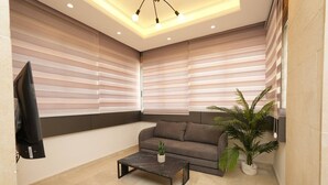 A modern living room with a sofa, a coffee table, and a TV mounted on the wall. - The Purple Apartment Badaro 3 Bdrm 24 7 Electric (Beirut)