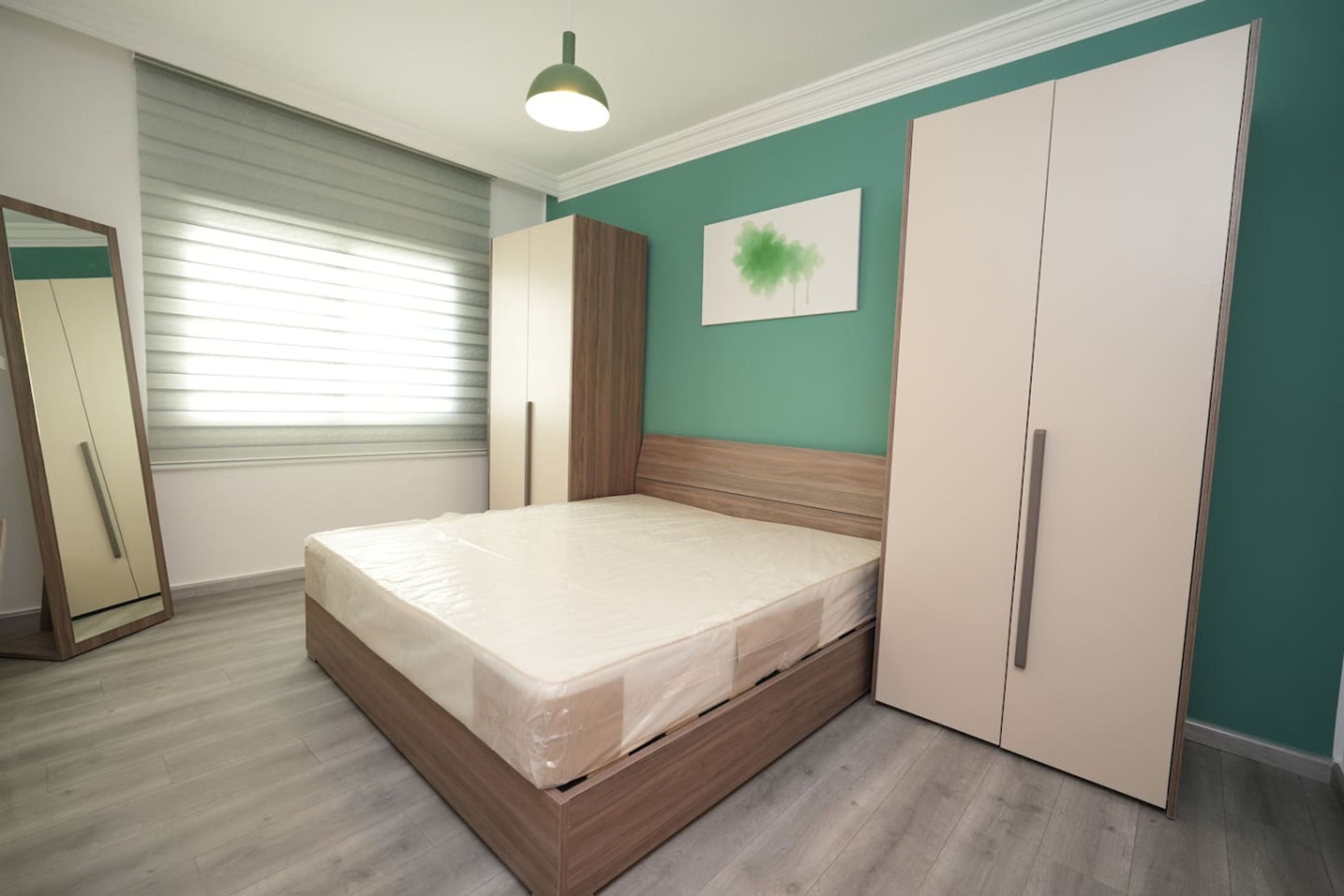 Un dormitorio con una cama de madera, un armario y un espejo.