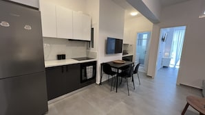 Ett modernt kök med en inbyggd ugn, en matplats med bord och stolar samt en tv som är monterad på väggen.