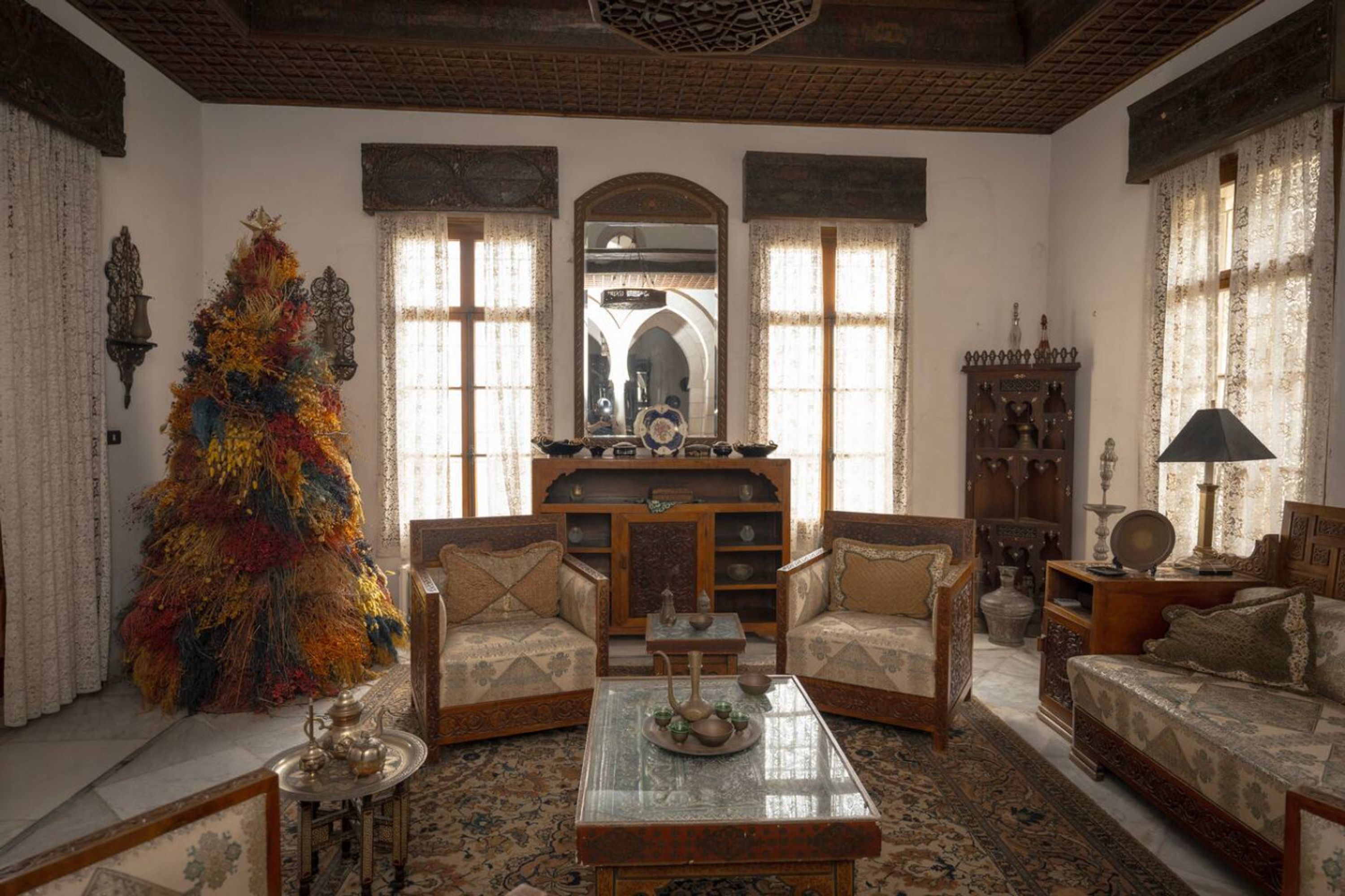A traditional living room with two sofas, a coffee table, and a decorative tree.