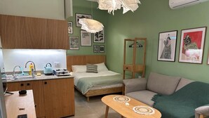 A compact room with a bed, a sofa, a small table, a kitchenette, and artwork on the walls. - Batroun s Lovely Studio (Batroun)