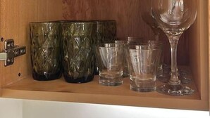 A wooden cabinet with shelves holding various glassware and ceramic mugs. - Batroun s Lovely Studio (Batroun)