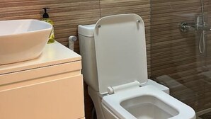 A bathroom with a modern design, featuring a toilet, a sink, and a shower. - Batroun s Lovely Studio (Batroun)