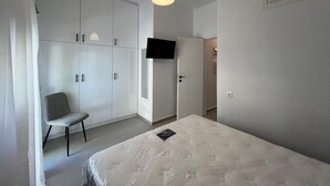 Et soveværelse med seng, stol, garderobeskab, fjernsyn og aircondition.