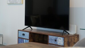 Ett modernt vardagsrum med en platt-TV på ett träställ, en klocka och ett inramat konstverk på väggen.