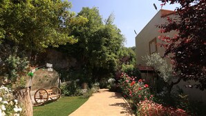 A garden pathway leading to a building with a rustic stone wall and a wooden cart. - Keserwan s Hillside Resort and Venue (Aazra Wil Aazr)
