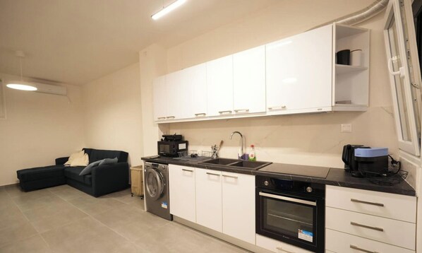 A compact kitchen with white cabinets, a built-in washing machine, and a dishwasher. - Comfortable Hideaway 10 min Walk Koukaki (Athens)