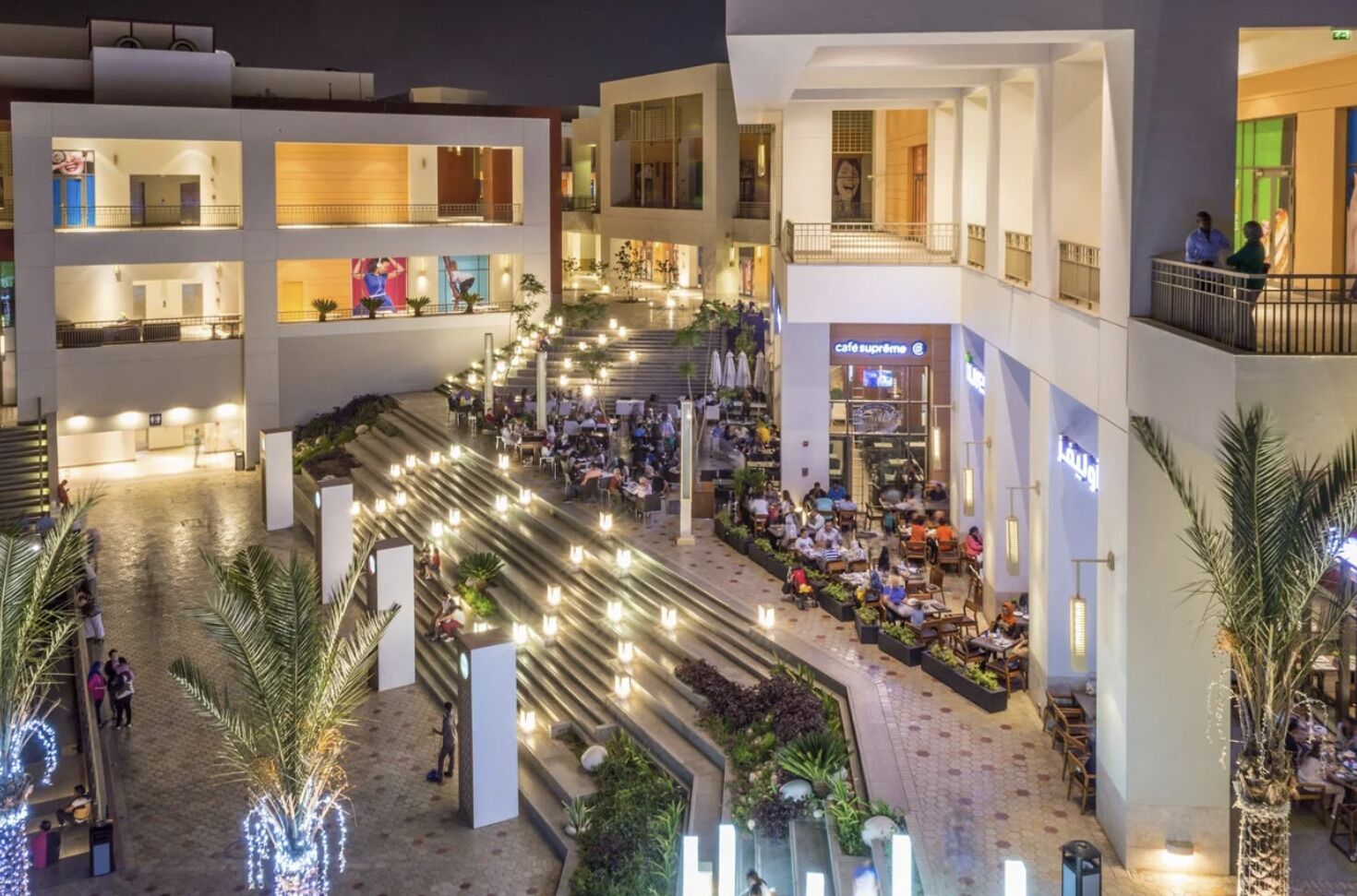 A multi-level atrium with outdoor seating areas, a café, and a staircase connecting the floors.