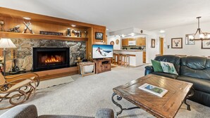 Una sala de estar acogedora con chimenea, televisor y sofá de cuero.