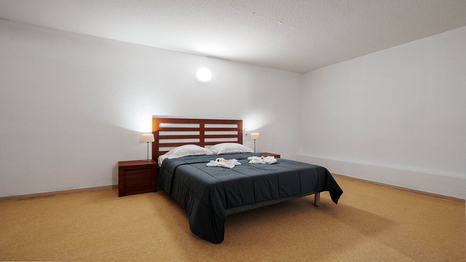 Ein Schlafzimmer mit einem Bett, einem Nachttisch und einer Wandlampe.