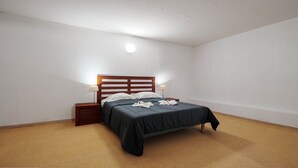 Un dormitorio con cama, mesita de noche y lámpara de pared.